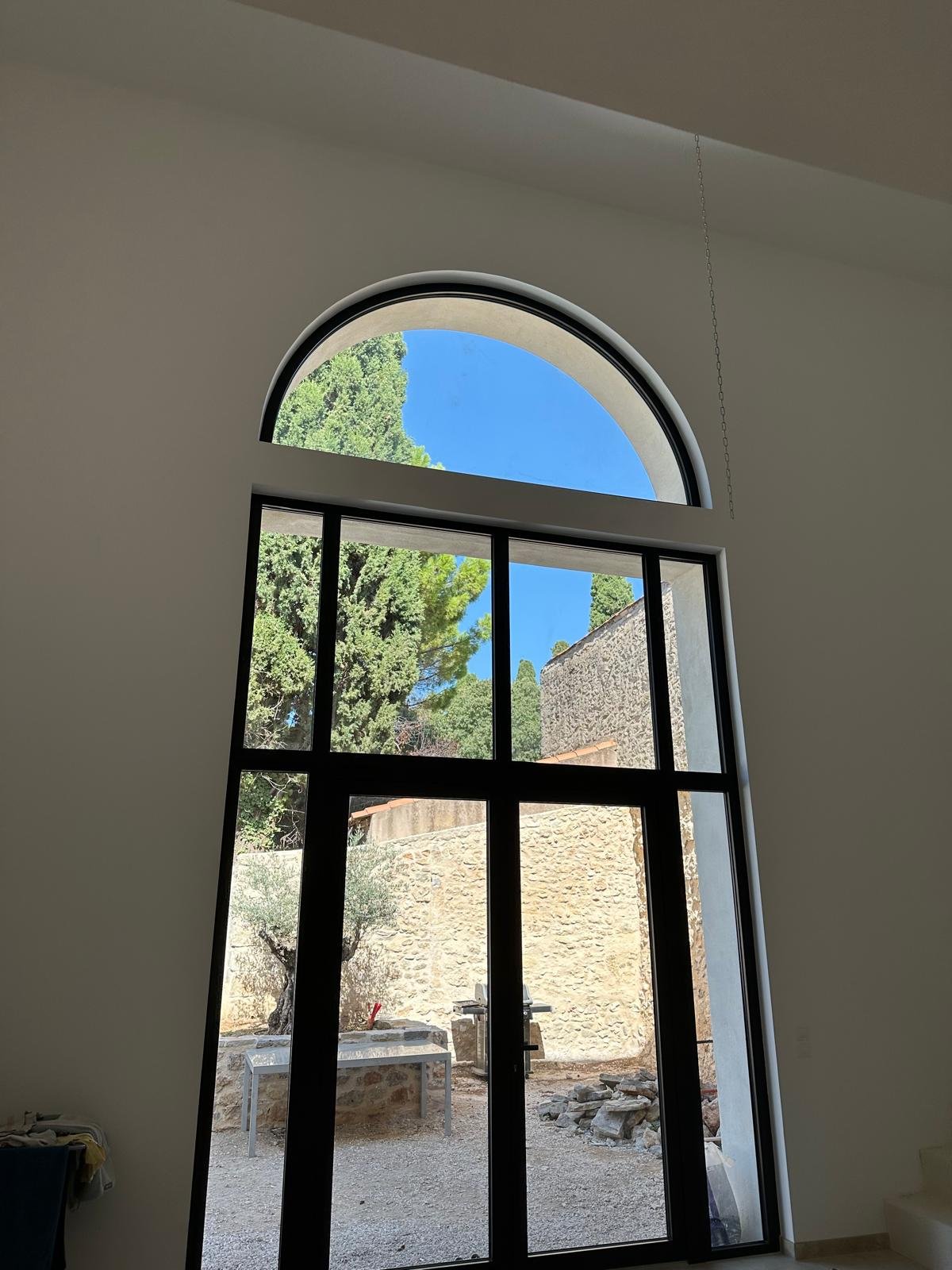 Rénovation de maison en pierre dans l'Hérault - grande baie vitrée cintrée avec vue jardin