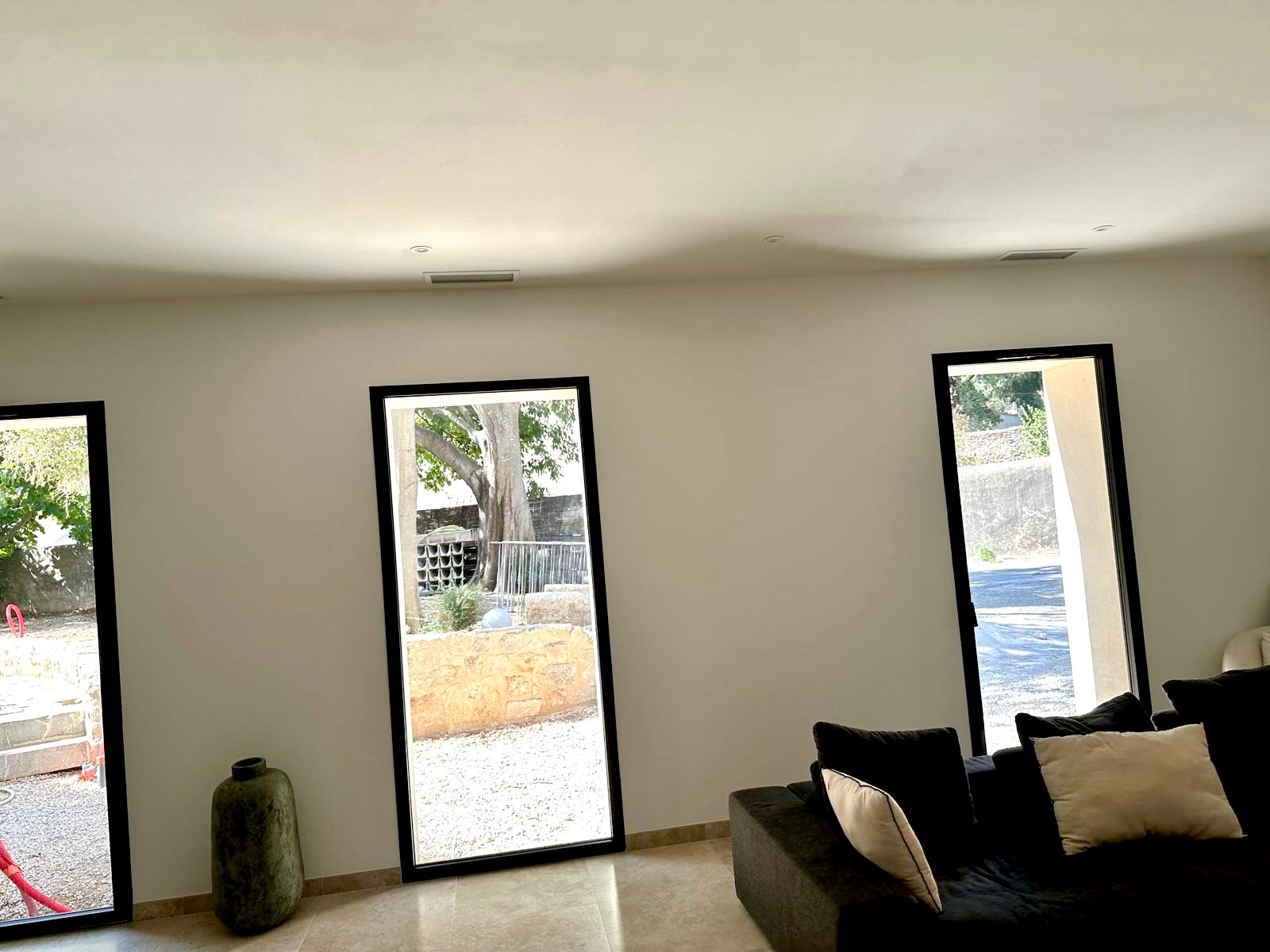 Rénovation de maison en pierre - salon avec grandes baies vitrées noires